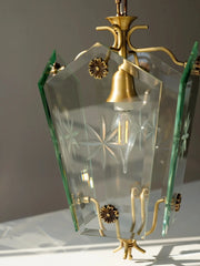 Decorative hanging lamp with glass shade and brass fixtures on a neutral background