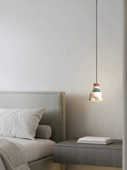 Modern bedroom with a bed and a side table featuring a pendant light.