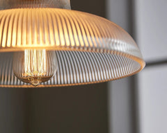 Close-up of a modern pendant light with a ribbed glass shade.