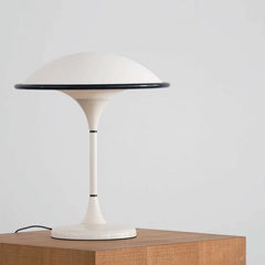 White table lamp with a black rim on a wooden surface against a light gray background