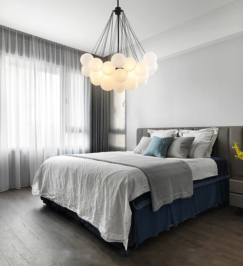 Modern bedroom with a bed, decorative pillows, and a stylish chandelier.