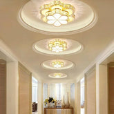A hallway illuminated by multiple gold and crystal flower flush mount ceiling lights.