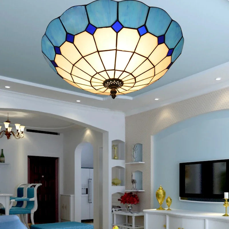 A blue stained glass ceiling light with a scalloped edge installed in a living room above a TV.