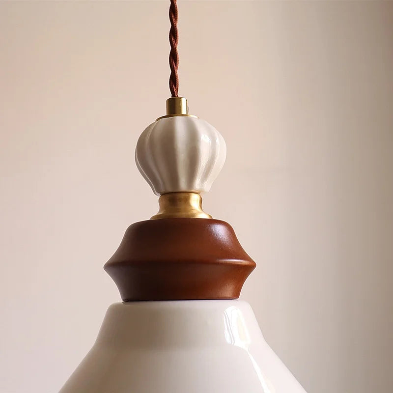 Close-up of a pendant light with a white, brown, and gold design against a beige background