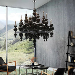 Black globe cluster pendant light with a modern, cascading design in a room with large windows.