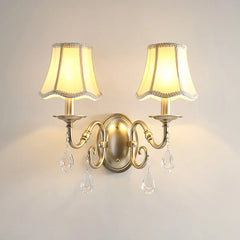 Pair of wall sconces with lampshades and crystal accents on a plain wall.