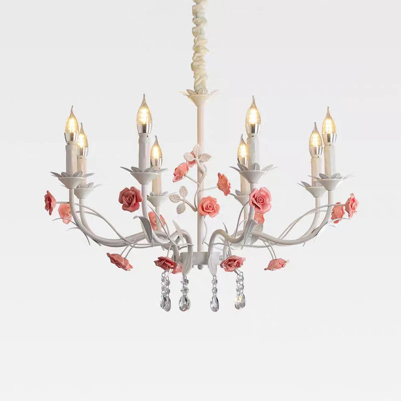 White floral crystal candelabra chandelier with pink roses and teardrop crystals, isolated on a white background.
