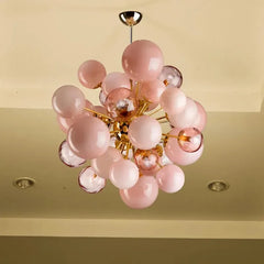Close-up view of a gold glass ball cluster pendant light with frosted and clear orbs against a cream-colored ceiling.