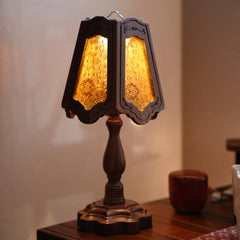 Side view of a table lamp featuring a scalloped-edge glass shade and a carved wooden base.