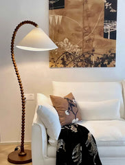 White sofa with decorative pillows and a wooden floor lamp in a living room setting.