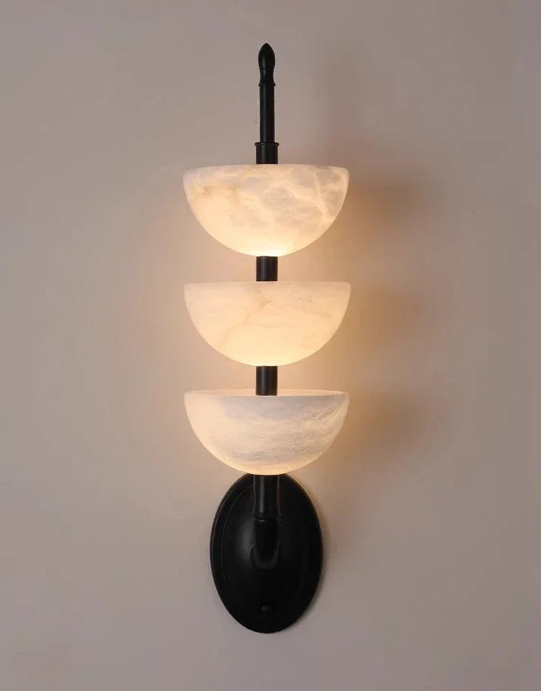 Wall-mounted light fixture with three tiered, bowl-like design on a plain background