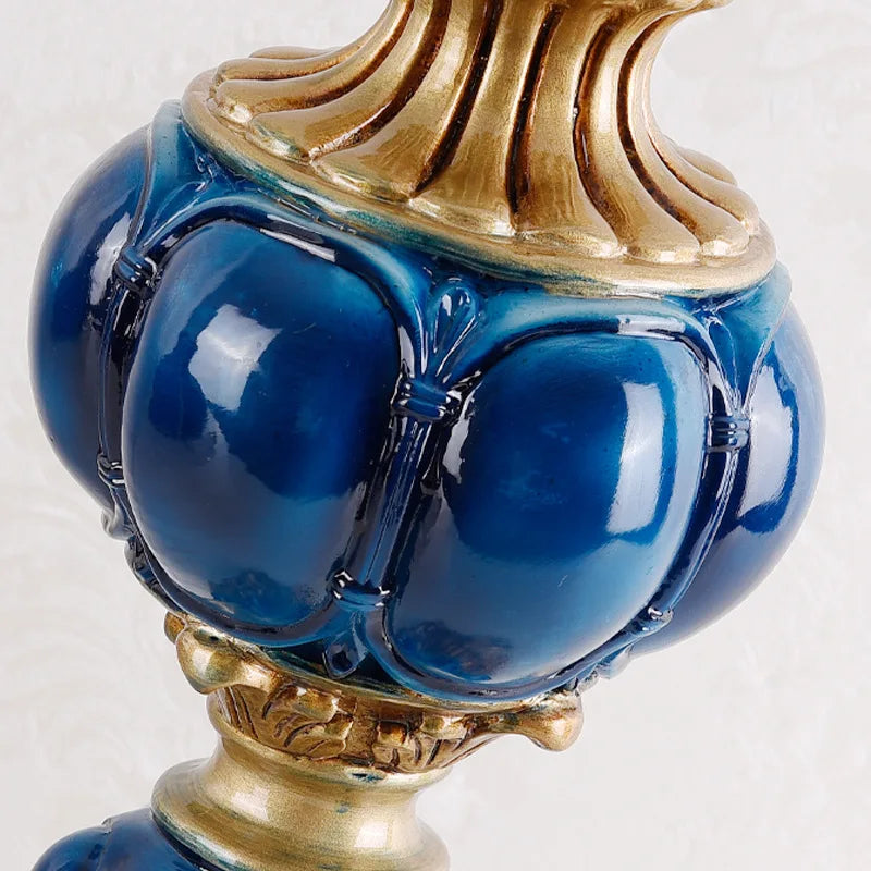 Detailed view of the ornate gold and blue ceramic base of a table lamp, showcasing its sculpted, bulbous design and glossy finish.