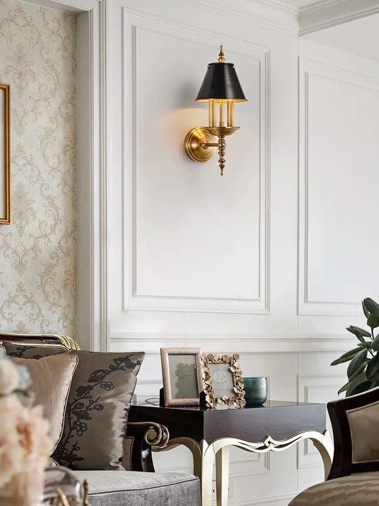 Decorative wall sconce in a stylish living room setting with floral wallpaper and a sofa.