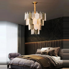 Modern bedroom with a chandelier, bed, and armchair.