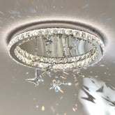 Round chrome pendant light with cascading crystals and butterfly charms casting light patterns on the ceiling.