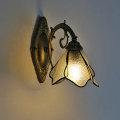 Decorative wall sconce with glass shade on a plain wall