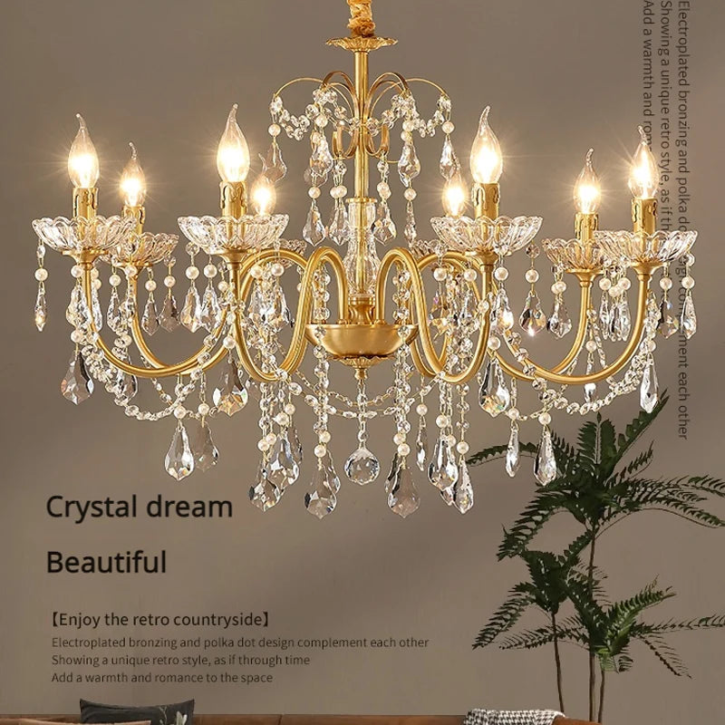 A close-up view of a luxurious gold chandelier adorned with numerous clear crystals and pearls, with warm light emanating from candle-shaped bulbs.