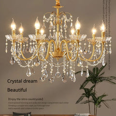 A close-up view of a luxurious gold chandelier adorned with numerous clear crystals and pearls, with warm light emanating from candle-shaped bulbs.