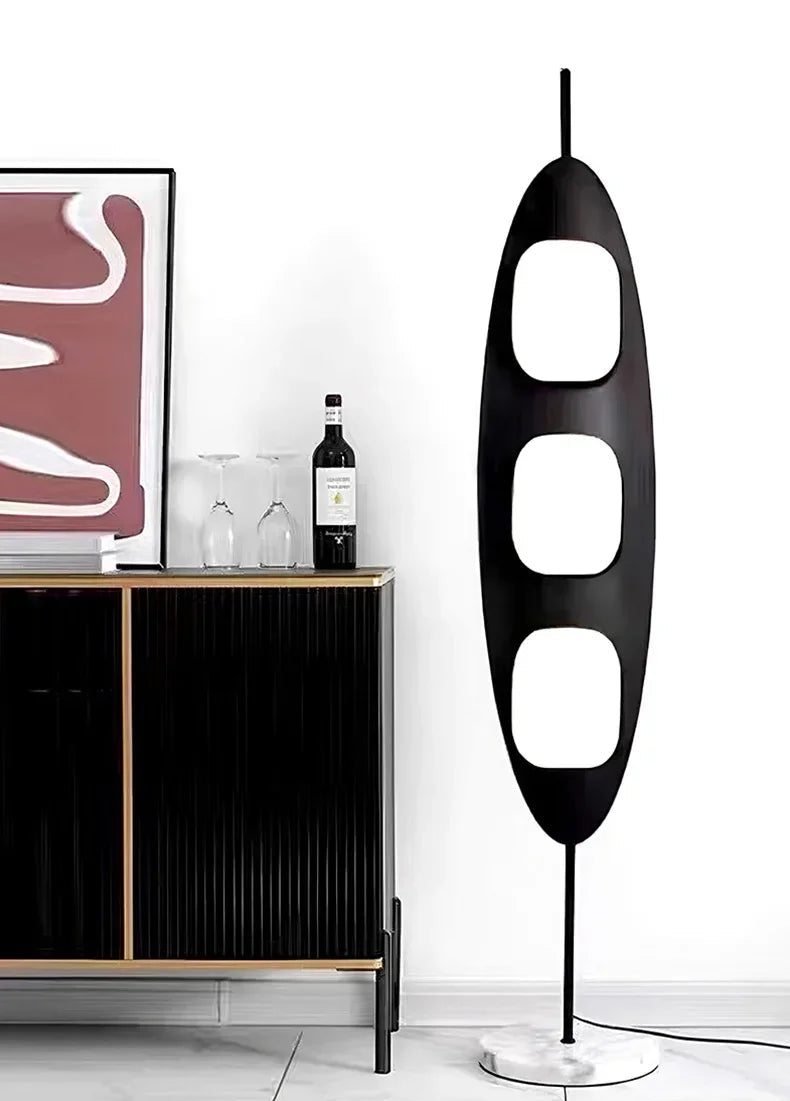 Modern black floor lamp next to a cabinet with decor items in a room.
