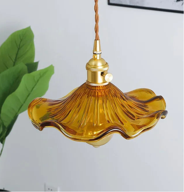 Amber glass pendant light with gold fixture against a white wall.