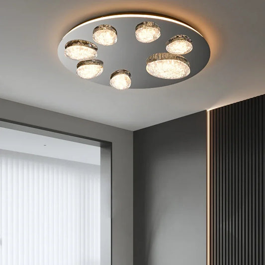 Round ceiling light fixture with multiple clear crystal globes on a polished chrome base, illuminated from within.