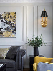 Living room with gray sofa, yellow chair, abstract art, and wall sconce.