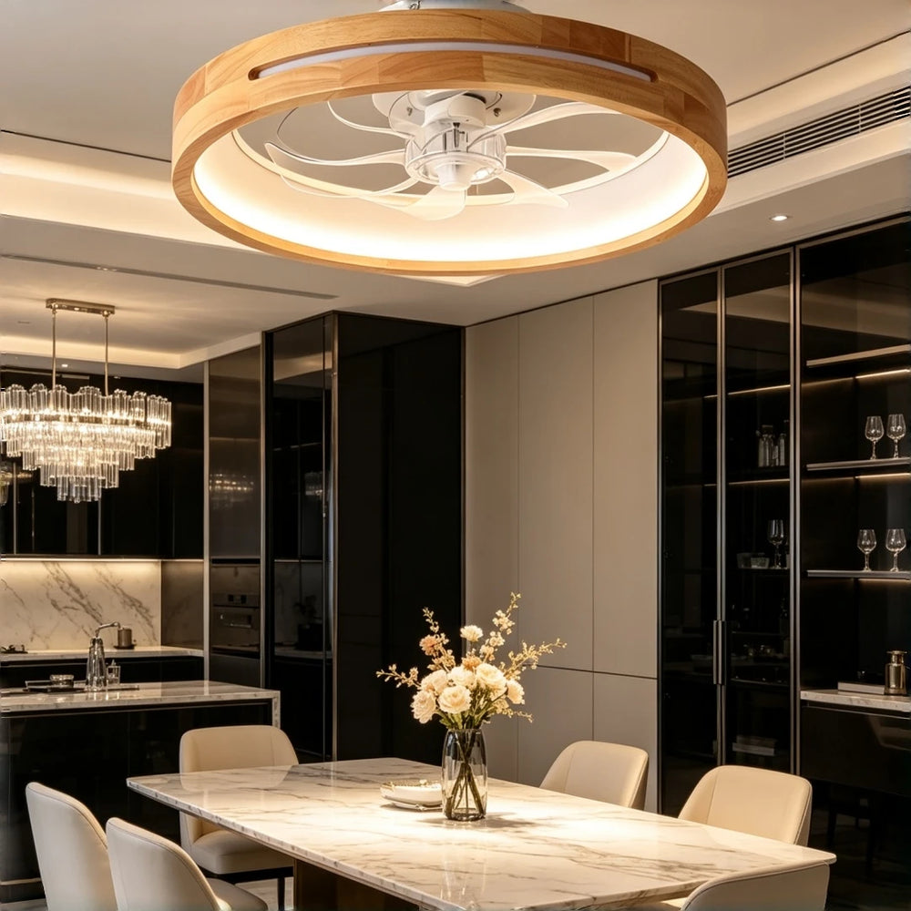 Ceiling fan light with a wooden frame and LED illumination over a modern dining table setup with a crystal chandelier visible in the background.
