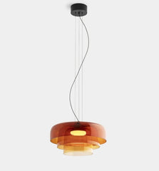 Modern pendant light with orange glass shade on a white background