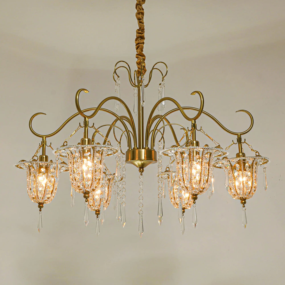 A wider view of the gold crystal chandelier in a room setting, highlighting its scale and the warm light it emits.