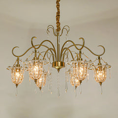 A wider view of the gold crystal chandelier in a room setting, highlighting its scale and the warm light it emits.