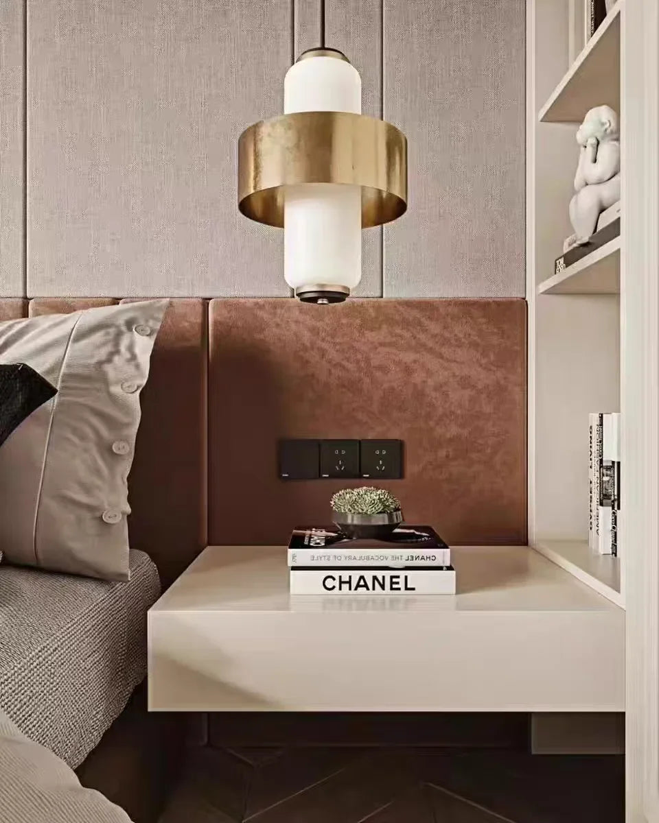 Close-up of a bedside table with a small plant and books, featuring a pendant light hanging above.