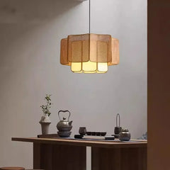A natural-toned rattan woven tiered pendant light hanging above a wooden table in a room with soft ambient lighting.