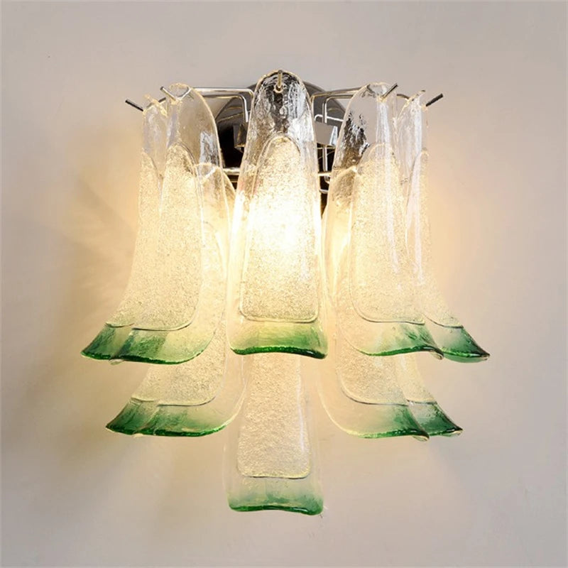 Green and clear glass petal wall sconce with a chrome finish, mounted on a white wall.