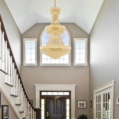 Luxurious chandelier hanging in a home interior with staircase and windows.