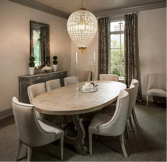 Dining room with an oval table and chairs, featuring a large crystal chandelier.