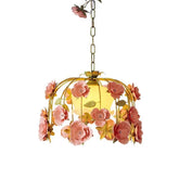 Side profile of a gold chandelier with pink floral decorations and a white glass globe light.
