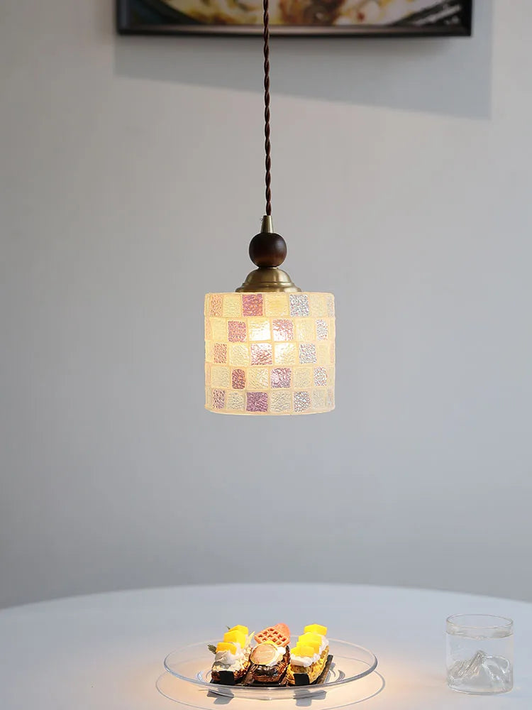 Small pendant light with a checkered shade hanging above a table with desserts.