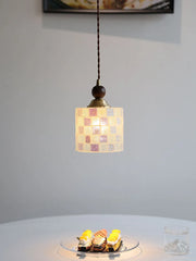 Small pendant light with a checkered shade hanging above a table with desserts.