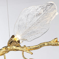 Decorative light fixture with gold branch and clear leaf design on a gray background