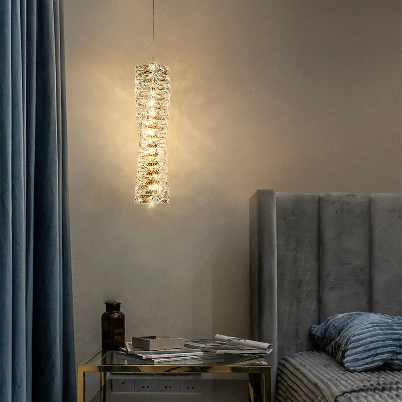Modern pendant light fixture in a bedroom setting with a gray headboard and decorative items.