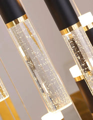 Decorative pendant lights with black, gold, and clear design on a neutral background