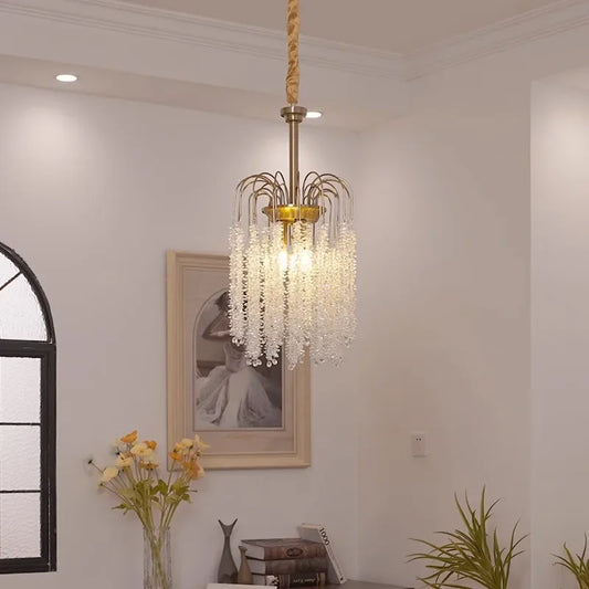 A gold cascading chandelier with crystal strands hangs from the ceiling in a well-lit room.