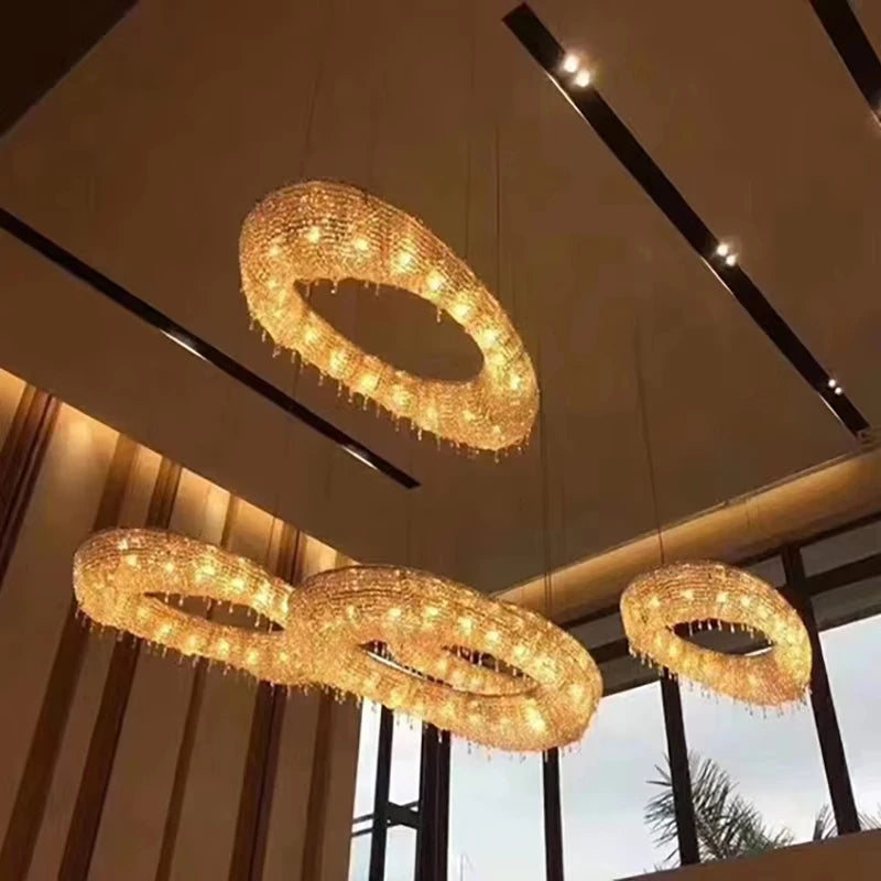 Four gold ring-shaped crystal chandeliers hanging from a ceiling.