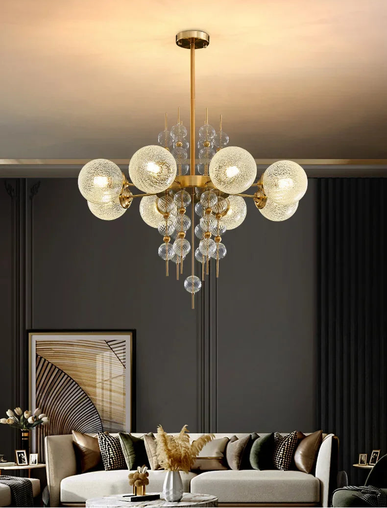 Modern chandelier hanging in a living room with a gray wall and sofa.