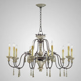 Distressed white and dark metal candle-style chandelier with 8 arms, featuring cream-colored candle covers and decorative wooden bead drops, shown against a white background.