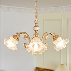 A gold chandelier with three frosted glass flower-shaped shades, highlighting the central bulb and curved arms.