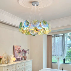 A colorful Murano-style glass disc chandelier with a polished metal frame, suspended from a white ceiling with decorative molding.