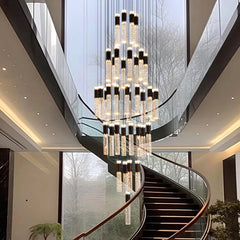 Luxurious chandelier hanging in a modern staircase with glass walls and wooden steps.