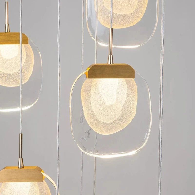 Modern pendant lights with glass shades and gold fixtures on a neutral background
