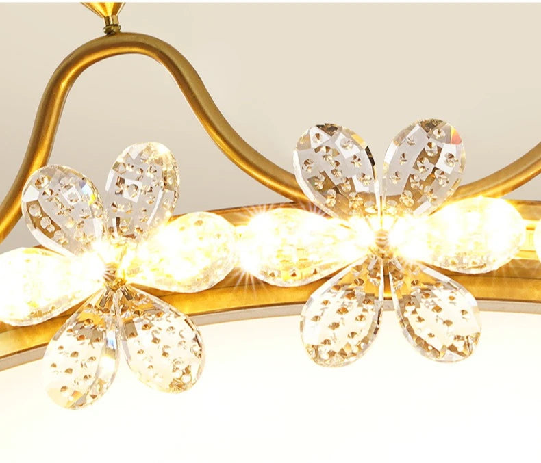 Ceiling light fixture with gold frame and crystal-like flower designs on a white background